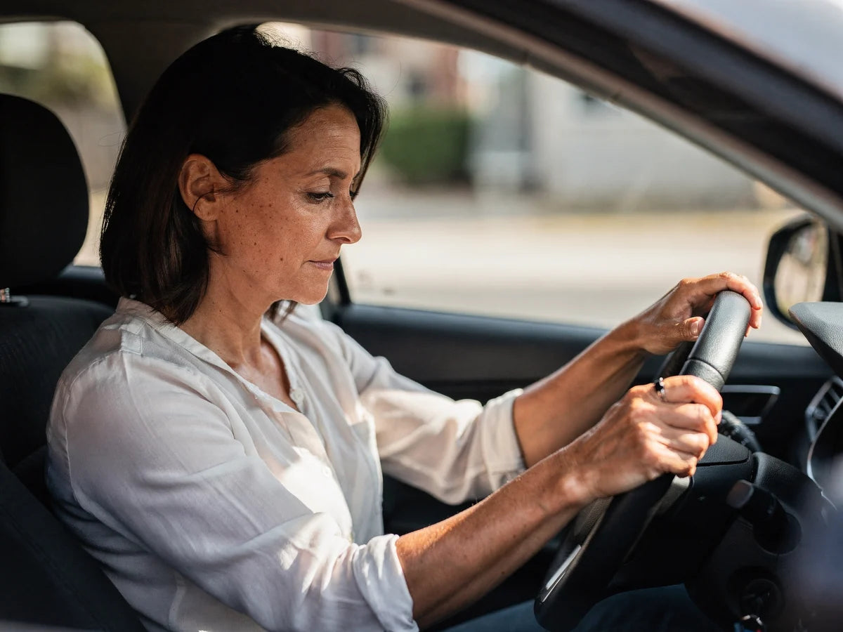 A woman in the driver's seat of a car with both hands on the wheel