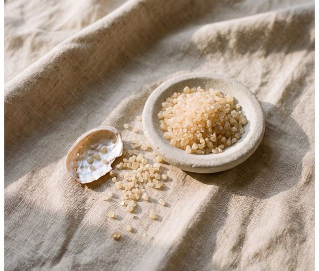 Amber collagen granules in a stone dish beside mother-of-pearl