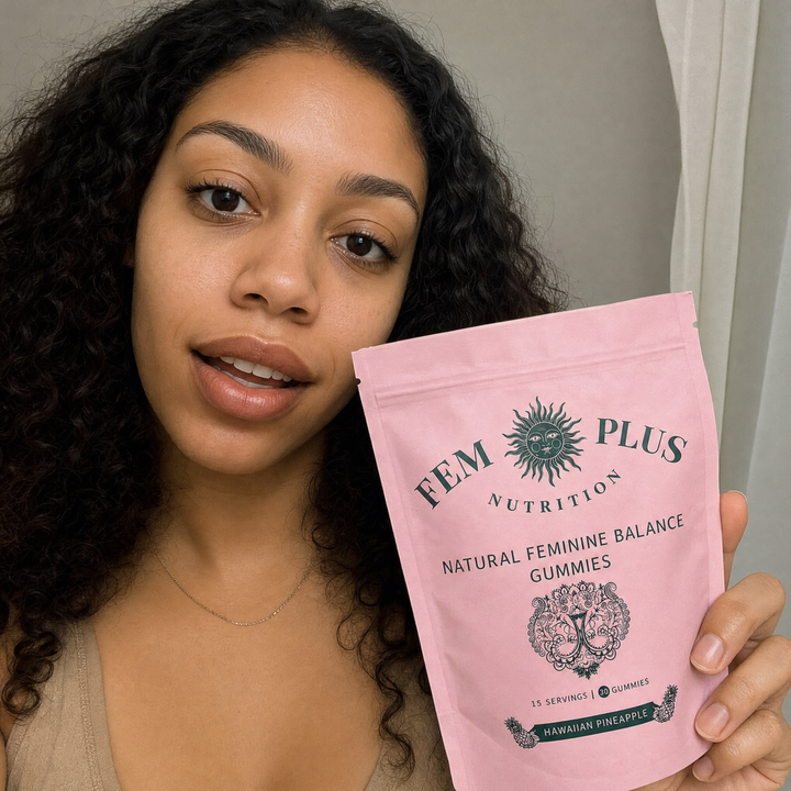 A woman with curly hair holding the FEM+ gummies pouch up to the camera