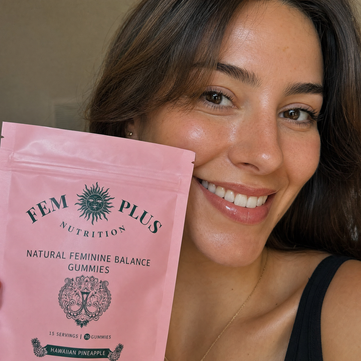 A woman holding the FEM+ gummies pouch beside her cheek, smiling
