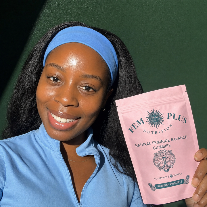 A woman in a blue collared top holding the FEM+ gummies pouch